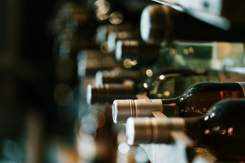 Bottiglie di vino raro allineate su una rastrelliera in cantina, luce calda e atmosfera intima